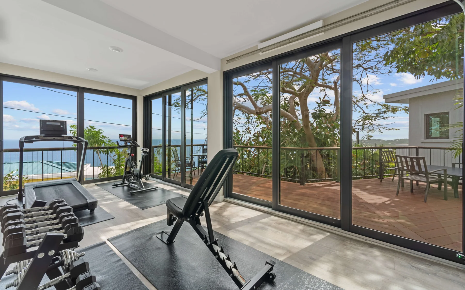 Fitness room with treadmill, bike, weights, and ocean view